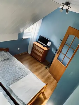 a bedroom with a bed and a desk with a television at Zielony Dom in Węglówka