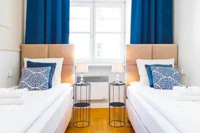 two beds in a room with blue curtains at Glamorous Apartment in heart of Old Town in Kraków