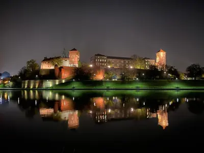 a view of a city at night with a body of water at Near the Royal Castle in Kraków