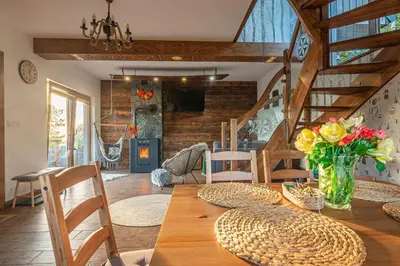 a dining room with a wooden table with flowers on it at Leśne Zacisze in Nowy Targ