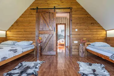 a bedroom with two beds and a wooden wall at Leśne Zacisze in Nowy Targ