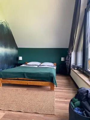 a bedroom with a bed with a green wall at Stodoła Nad Skawą in Sucha Beskidzka