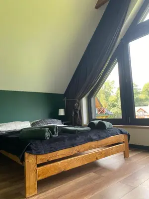 a bedroom with a wooden bed with a large window at Stodoła Nad Skawą in Sucha Beskidzka