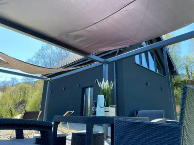 a patio with chairs and a table with awning at Stodoła Nad Skawą in Sucha Beskidzka