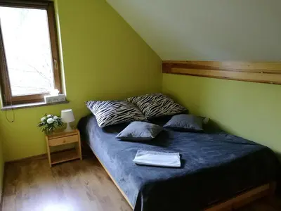 a bedroom with a bed with a blue comforter and a window at Domek w Zawoi Chwilo Trwaj in Zawoja