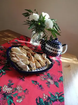 a plate of pastries on a table with a vase of flowers at Domek w Zawoi Chwilo Trwaj in Zawoja