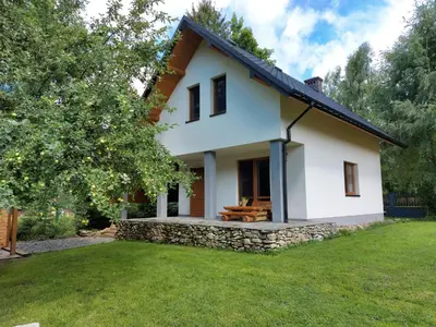 a white house with a bench on a yard at Domek w Zawoi Chwilo Trwaj in Zawoja