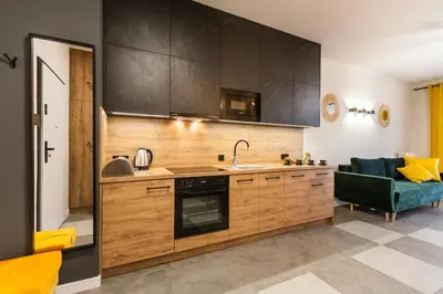 a kitchen with wooden cabinets and a green couch at Vintage Rakowicka Apartment in Kraków