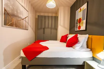 a bedroom with a bed with red pillows at Vintage Rakowicka Apartment in Kraków