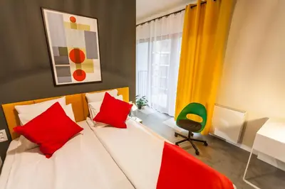 a bedroom with a bed with red pillows and a desk at Vintage Rakowicka Apartment in Kraków