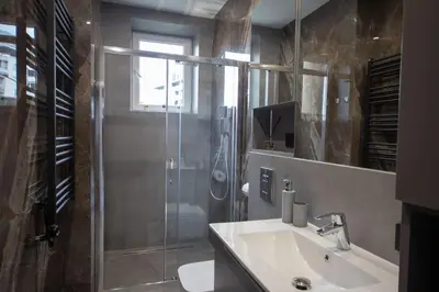 a bathroom with a glass shower and a sink at Kotlarska Apartments in Kraków