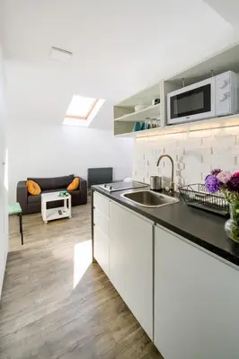 a white kitchen with a sink and a living room at Modern apartment in the very central location 18 in Kraków