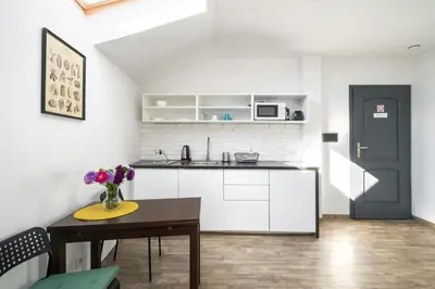 a kitchen with white cabinets and a table with flowers at Modern aparment in the very central location 19 in Kraków