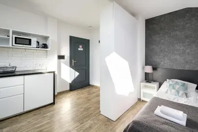 a bedroom with a bed and a kitchen with a microwave at Modern aparment in the very central location 19 in Kraków