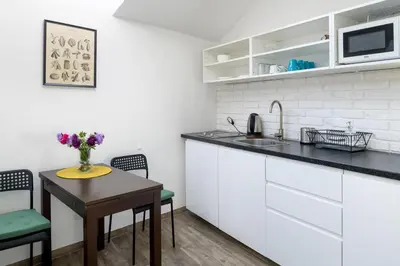 a kitchen with white cabinets and a small table with flowers at Modern aparment in the very central location 19 in Kraków