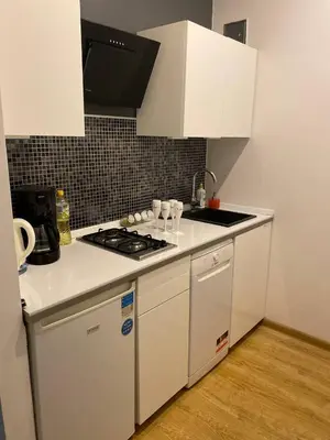 a kitchen with a stove and white cabinets at LOTOS Hostel in Kraków