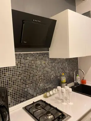 a kitchen counter with a stove top with a microwave at LOTOS Hostel in Kraków