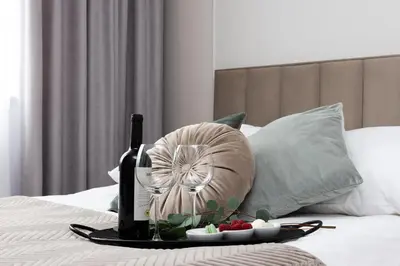 a tray with a bottle of wine and a plate of fruit on a bed at Green Residence Orawska 5 in Kraków