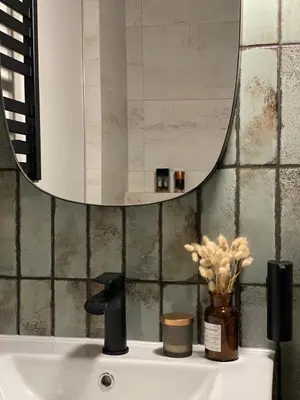 a bathroom sink with a mirror and a vase of flowers at Green Residence Orawska 5 in Kraków