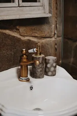 a bathroom sink with a brass faucet and two candles at Ojcowski Zakątek-domek z balią oraz drewniany domek do wynajęcia in Wola Kalinowska