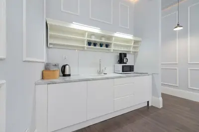 a white kitchen with white cabinets and a microwave at Perła Starego Miasta Kamienica Czapskich by Noclegi Renters in Kraków