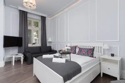 a white bedroom with a bed and a couch at Perła Starego Miasta Kamienica Czapskich by Noclegi Renters in Kraków