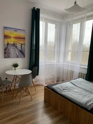 a bedroom with a bed and a table and windows at Cracow Old Town Rooms in Kraków