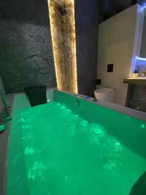 a bath tub with green water in a bathroom at Silver Shine jacuzzi in Kraków