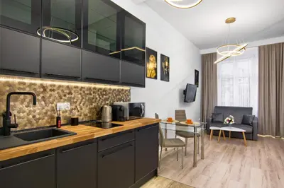 a kitchen with black cabinets and a table with chairs at Silver Shine jacuzzi in Kraków