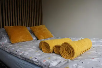 a bed with yellow blankets and pillows on it at NikoApartments - MiniApartment 2+2 in Kraków