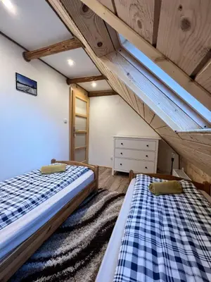 two beds in a room with wooden ceilings at Pokoje gościnne 28 w skosie in Zawadka
