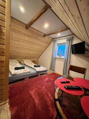 two beds in a room with a red rug at Pokoje gościnne 28 w skosie in Zawadka
