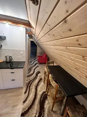 a room with a wooden wall with a bench and a table at Pokoje gościnne 28 w skosie in Zawadka