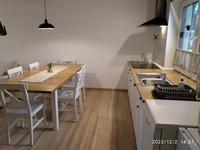 a kitchen with a wooden table and a sink at Leśny Domek in Las