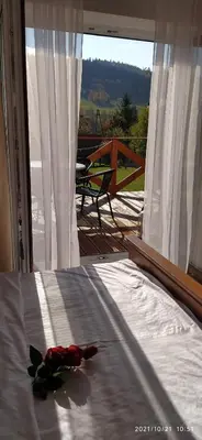 a flower on a bed in a room with a window at Leśny Domek in Las