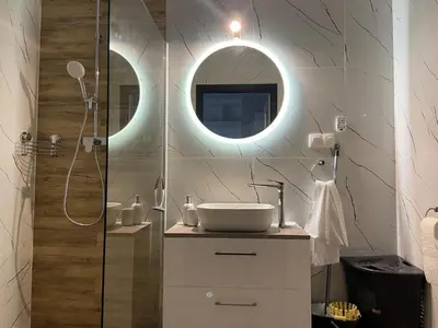 a bathroom with a sink and a shower with a mirror at krakow dream apartment in Kraków
