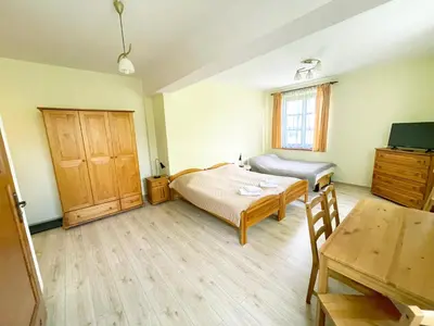 a bedroom with two beds and a chair and a window at Villa Gorczańska in Rabka