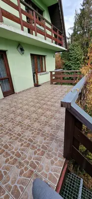 a building with a stone patio with a bench in front at Apartament Leśny in Nowy Targ