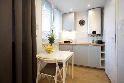 a small white kitchen with a white table and chairs at Quiet studio in the Old Town in Kraków