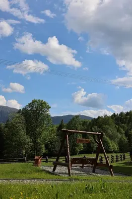 a wooden bench in a field with mountains in the background at Chatki Osada Babia Raj Zawoja in Zawoja