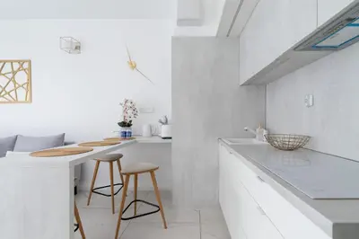 a white kitchen with two stools and a counter at Modern Apartment Cracow Old Town by Noclegi Renters in Kraków
