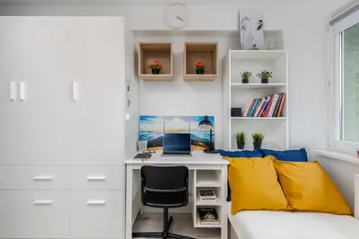 a bedroom with a desk and a bed with a laptop at Czarnowiejska Micro Studio in Kraków