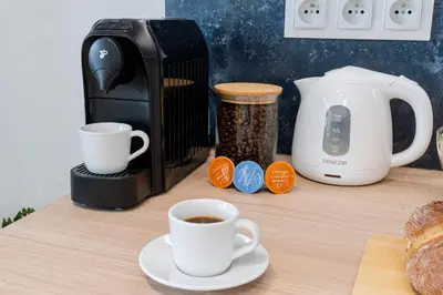a cup of coffee on a table with a coffee maker at Czarnowiejska Micro Studio in Kraków