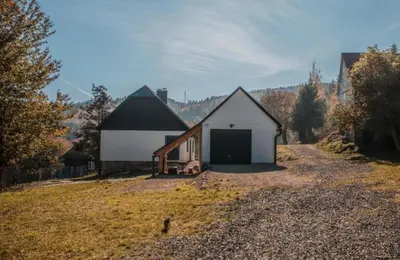 a white barn with a black roof on a field at Beskidzka Oaza in Targanice
