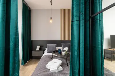 a bedroom with green curtains and a bed with a table at Kraków Rynek Podgórski Apartment by Noclegi Renters in Kraków