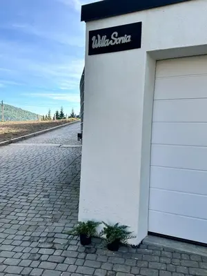 a white building with a garage with a sign on it at Willa Sonia Zawoja in Zawoja