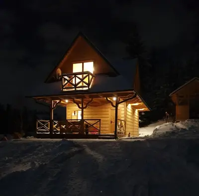 a lit up cabin in the snow at night at Domek w górach pod Jodłami in Nowy Targ
