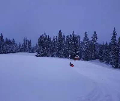 a person riding a snowmobile down a snow covered slope at Domek w górach pod Jodłami in Nowy Targ