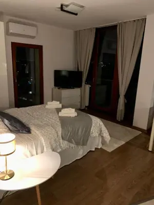 a bedroom with a bed and a television and a chair at City view Wellness Apartment swim&steam&relax in Kraków