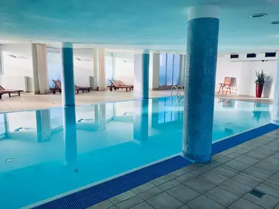 a large swimming pool with blue water in a building at City view Wellness Apartment swim&steam&relax in Kraków